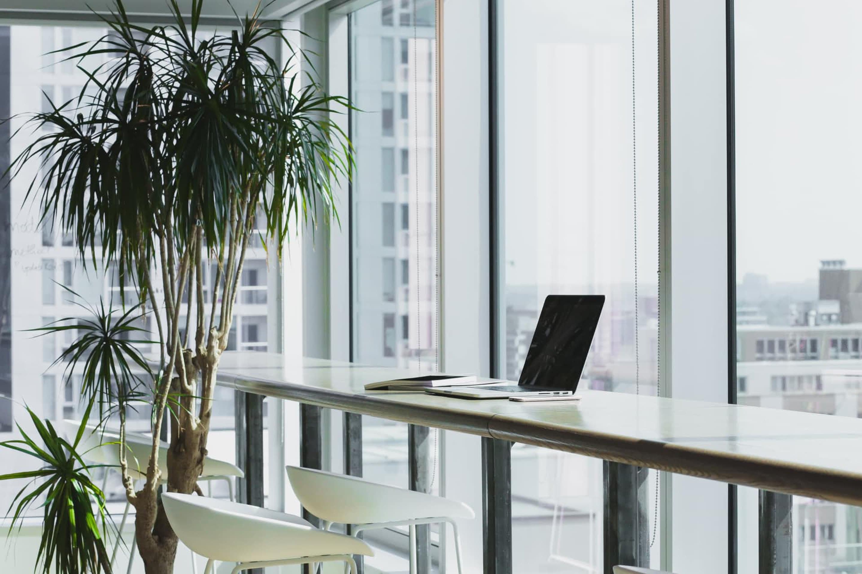 Laptop auf einer Theke vor einer Fensterfront mit Stadtblick